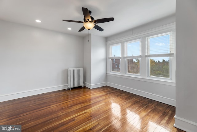 empty room with hardwood / wood-style floors, radiator, and ceiling fan