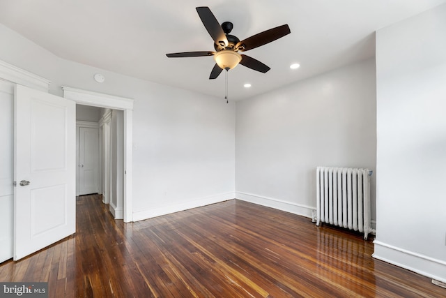 spare room featuring ceiling fan, radiator heating unit, and dark wood-type flooring