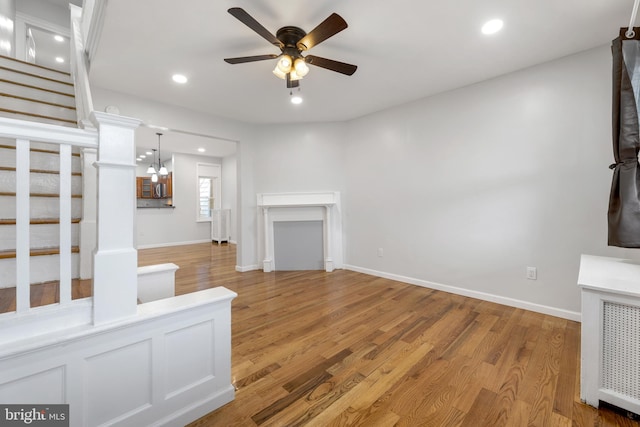 unfurnished living room featuring hardwood / wood-style floors and ceiling fan with notable chandelier