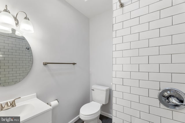 bathroom with tiled shower, vanity, and toilet