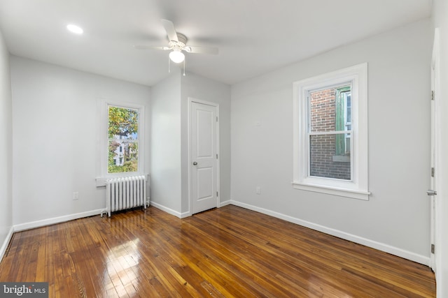 unfurnished room featuring ceiling fan, dark hardwood / wood-style flooring, and radiator