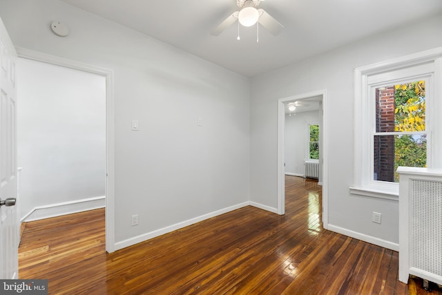 spare room with ceiling fan, dark hardwood / wood-style flooring, and radiator heating unit