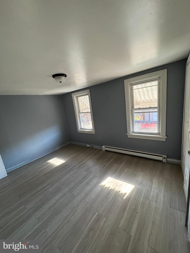 spare room with hardwood / wood-style floors, lofted ceiling, and a baseboard heating unit