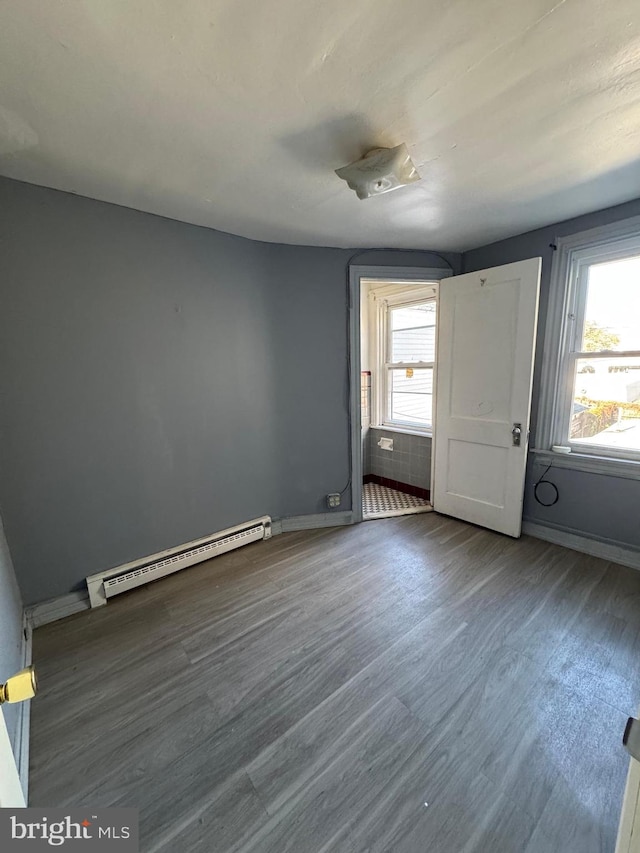 empty room with a baseboard heating unit and hardwood / wood-style floors