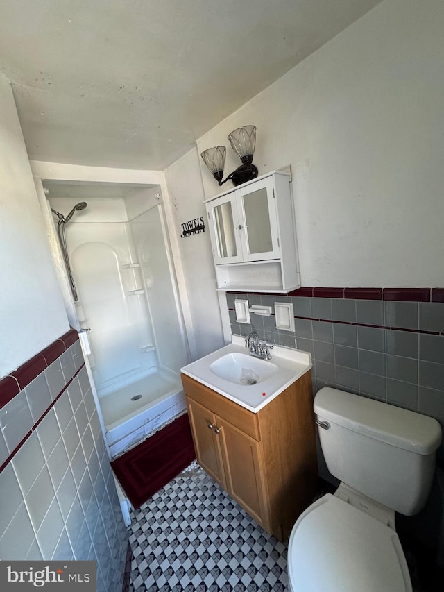 bathroom featuring tile walls, walk in shower, toilet, and vanity