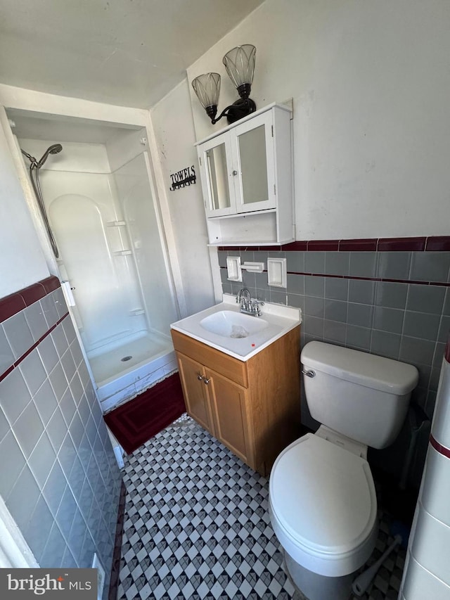 bathroom featuring walk in shower, vanity, tile walls, and toilet