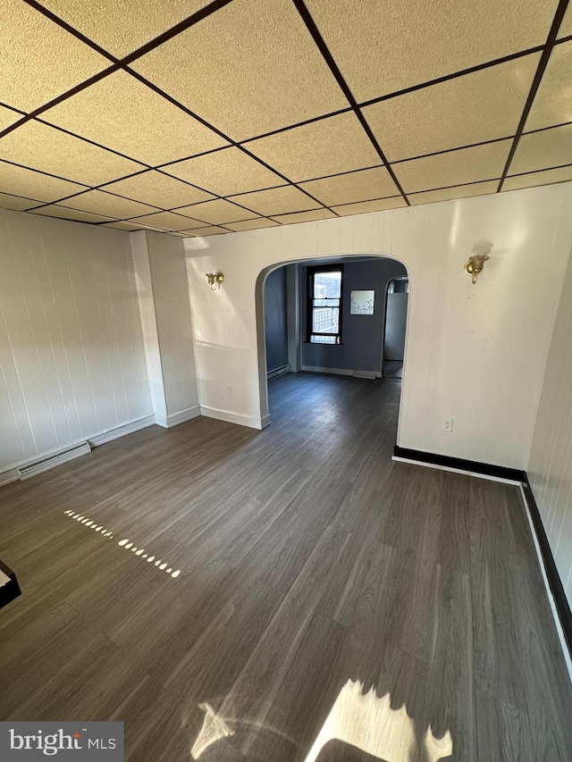 spare room with a drop ceiling and dark wood-type flooring