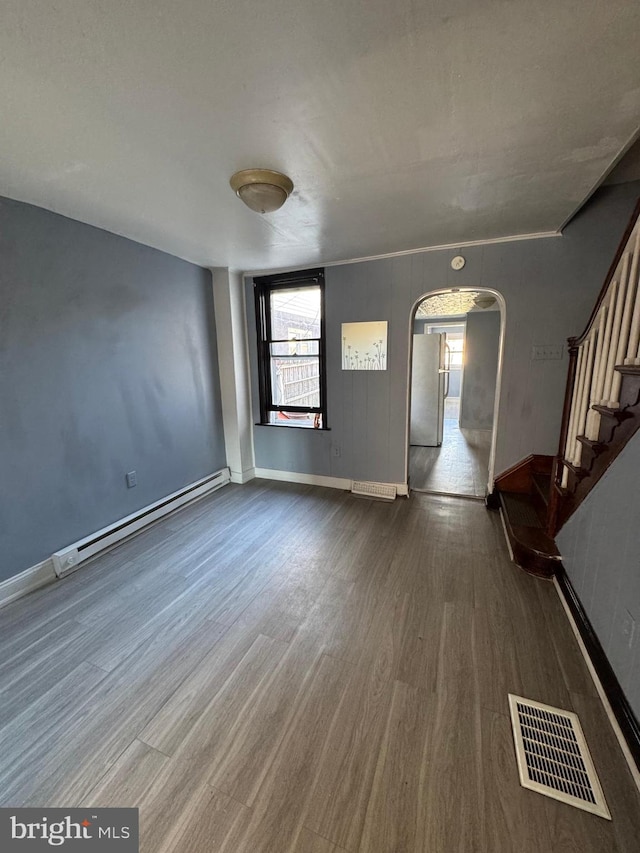 empty room with wood-type flooring and baseboard heating