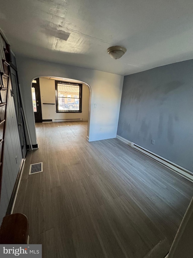 unfurnished room featuring hardwood / wood-style flooring and a baseboard radiator