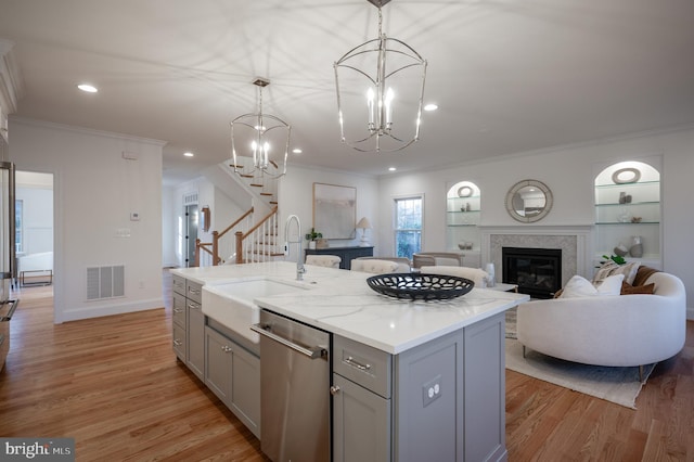 kitchen with gray cabinetry, dishwasher, a kitchen island with sink, hanging light fixtures, and light wood-type flooring