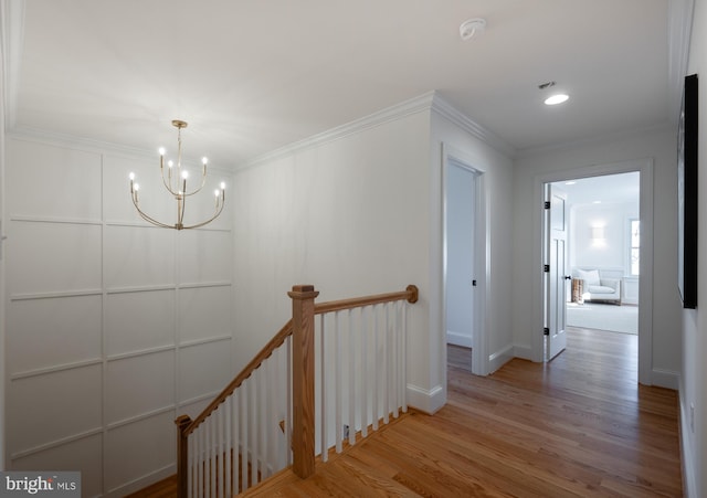 corridor featuring crown molding, wood-type flooring, and an inviting chandelier