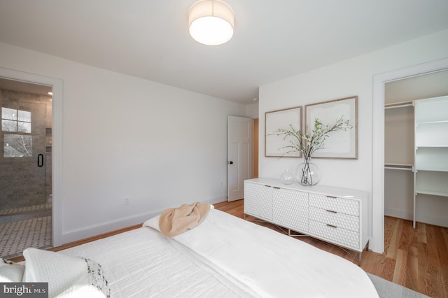 bedroom with connected bathroom, a walk in closet, a closet, and light wood-type flooring