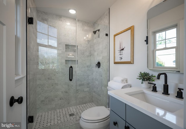 bathroom featuring vanity, toilet, and a shower with shower door