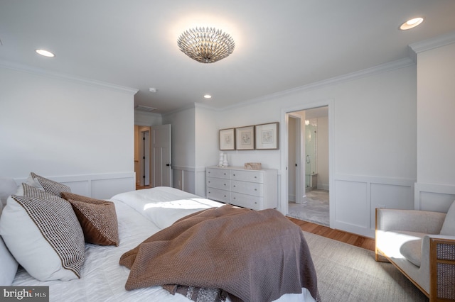 bedroom featuring ensuite bath, light wood-type flooring, and ornamental molding