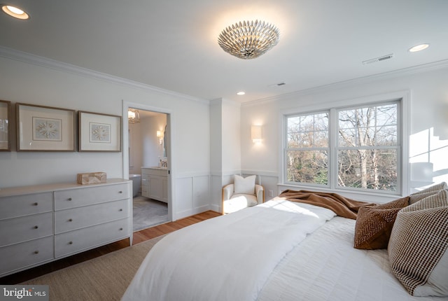 bedroom featuring hardwood / wood-style floors, connected bathroom, and crown molding