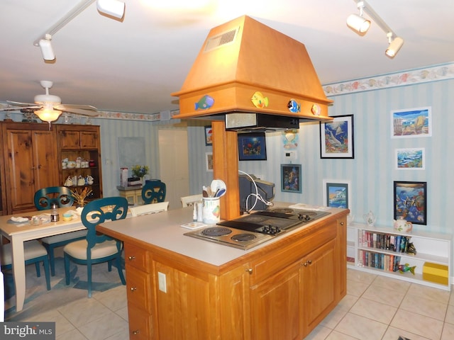 kitchen with custom range hood, ceiling fan, stainless steel stovetop, a center island, and light tile patterned flooring