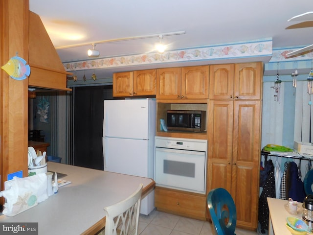 kitchen featuring light tile patterned floors, white appliances, and track lighting