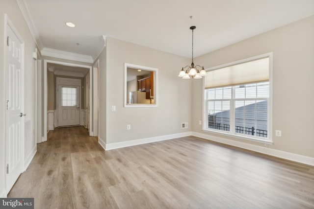 unfurnished room with light wood-type flooring, an inviting chandelier, and crown molding