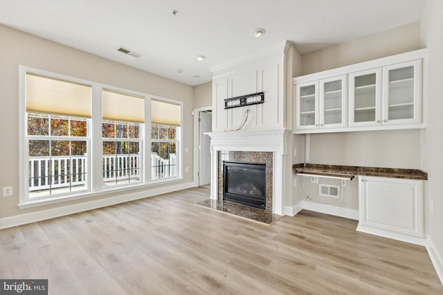 unfurnished living room with light wood-type flooring and a high end fireplace