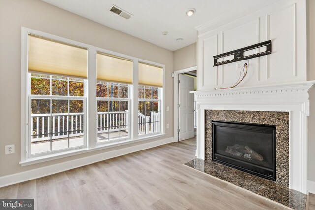 unfurnished living room featuring a fireplace, a healthy amount of sunlight, and light hardwood / wood-style flooring