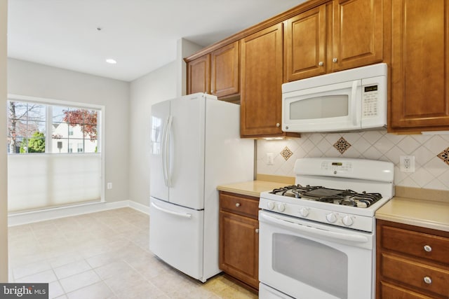 kitchen featuring white appliances, decorative backsplash, and light tile patterned flooring