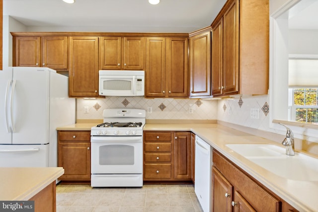 kitchen with light tile patterned floors, white appliances, sink, and backsplash