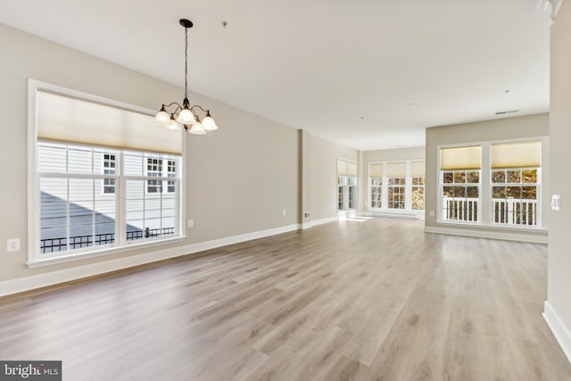 unfurnished living room featuring light wood-type flooring and an inviting chandelier