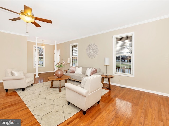 living room featuring hardwood / wood-style flooring, ceiling fan, ornate columns, and crown molding