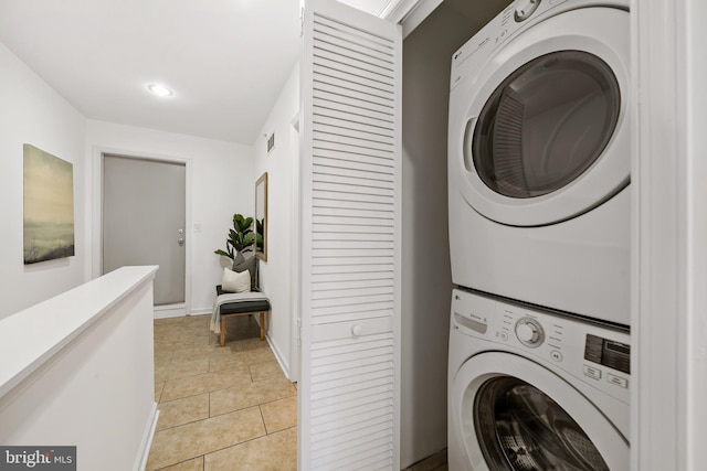 washroom featuring stacked washer and dryer and light tile patterned floors