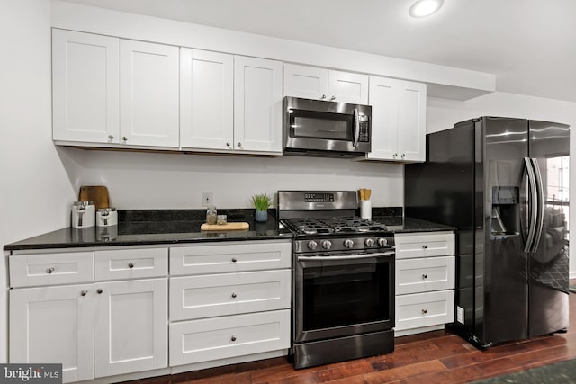 kitchen featuring dark hardwood / wood-style flooring, white cabinetry, appliances with stainless steel finishes, and dark stone countertops