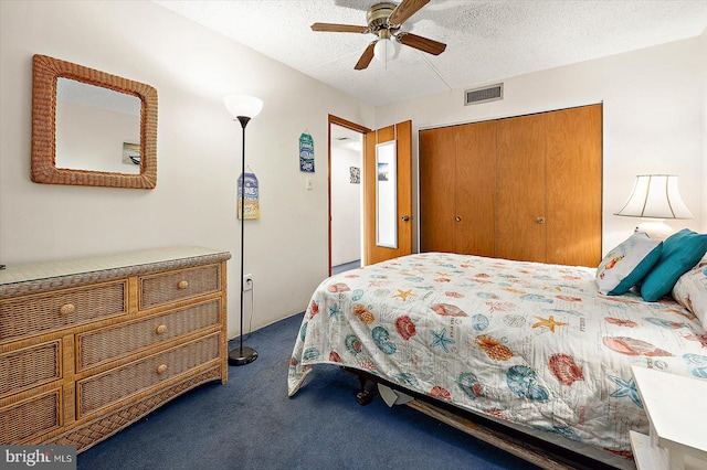 bedroom featuring ceiling fan, dark colored carpet, a closet, and a textured ceiling