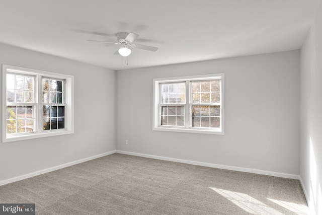 carpeted spare room with ceiling fan and plenty of natural light