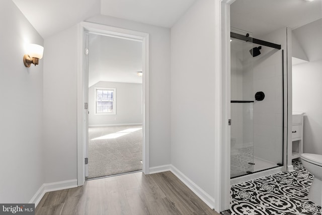 bathroom with walk in shower, hardwood / wood-style floors, lofted ceiling, and toilet