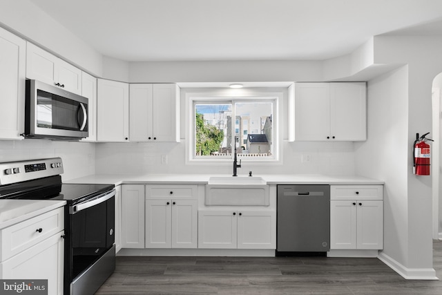 kitchen with stainless steel appliances, white cabinets, sink, dark hardwood / wood-style floors, and backsplash