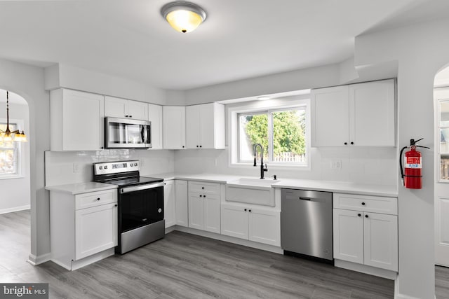 kitchen featuring stainless steel appliances, decorative backsplash, hardwood / wood-style floors, sink, and white cabinets