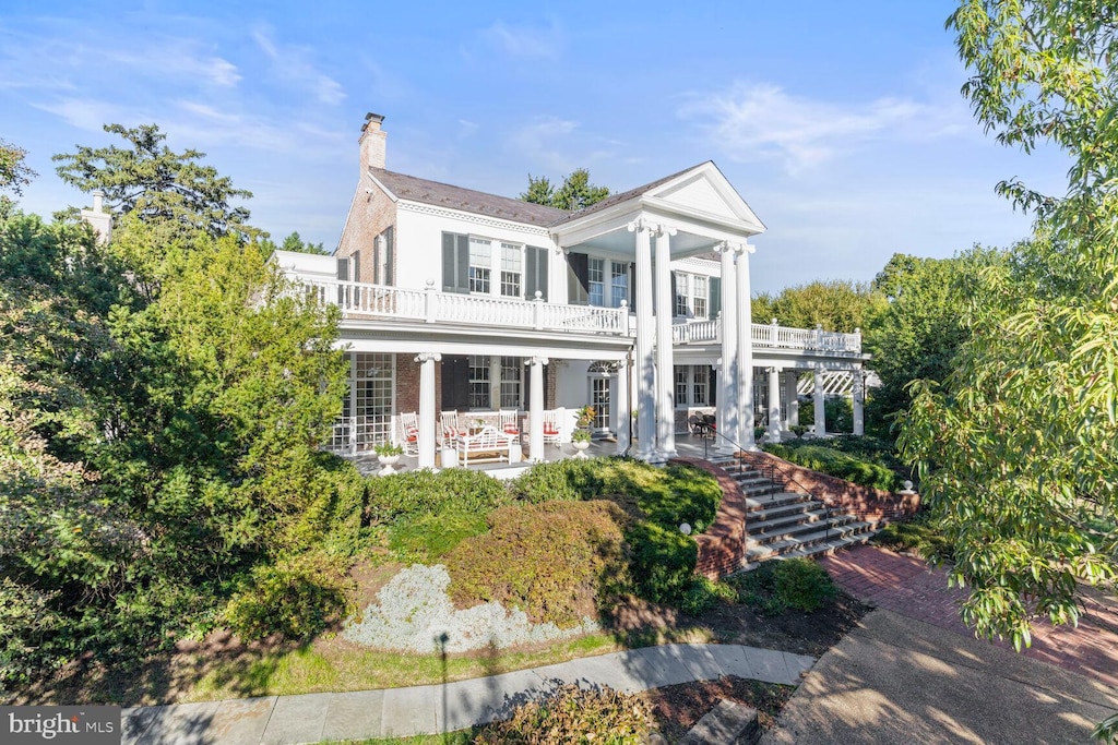 greek revival inspired property featuring a balcony and covered porch