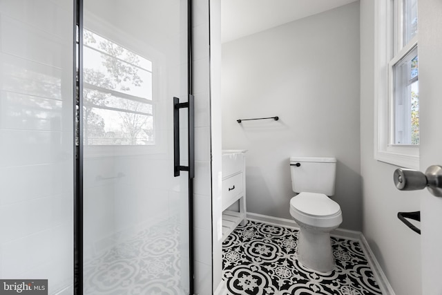 bathroom with plenty of natural light, toilet, baseboards, and a shower stall