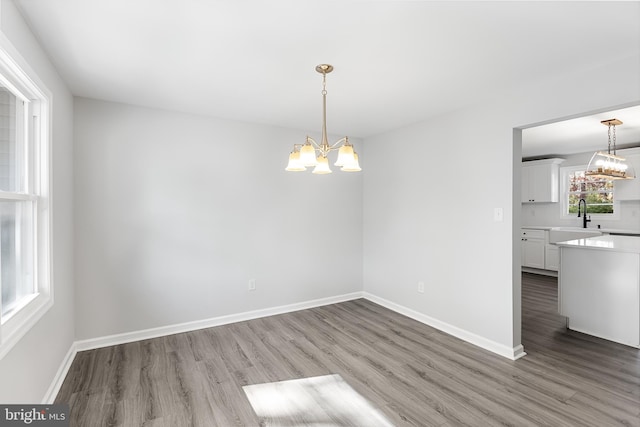 unfurnished dining area with hardwood / wood-style flooring, sink, and an inviting chandelier