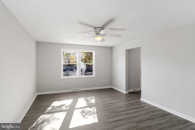 empty room with ceiling fan, dark wood-type flooring, and baseboards
