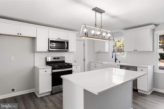 kitchen featuring appliances with stainless steel finishes, a sink, tasteful backsplash, dark wood-style floors, and white cabinetry