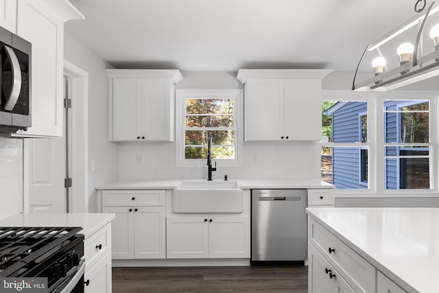 kitchen with stainless steel appliances, light countertops, a sink, and backsplash