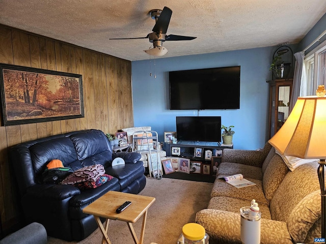 living room with carpet flooring, wood walls, a textured ceiling, and ceiling fan