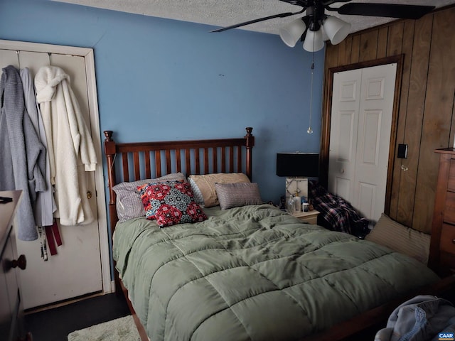 bedroom with wooden walls, a textured ceiling, carpet, and ceiling fan