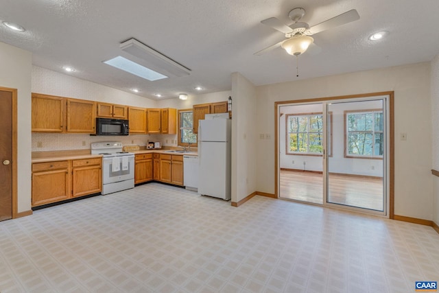 kitchen featuring white appliances, ceiling fan, a textured ceiling, and vaulted ceiling