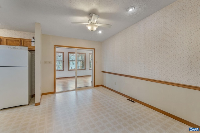 kitchen featuring a textured ceiling, ceiling fan, and white refrigerator