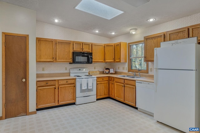 kitchen with lofted ceiling with skylight, white appliances, sink, and a textured ceiling