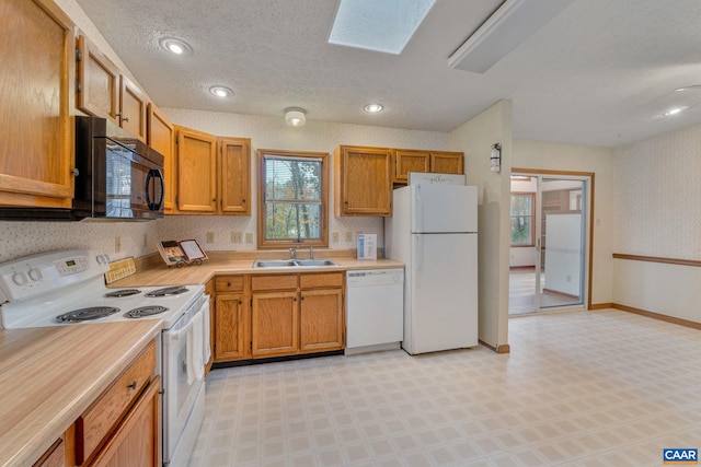 kitchen with white appliances, a textured ceiling, sink, and a skylight