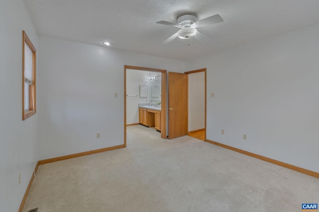 spare room with sink, a textured ceiling, light carpet, and ceiling fan