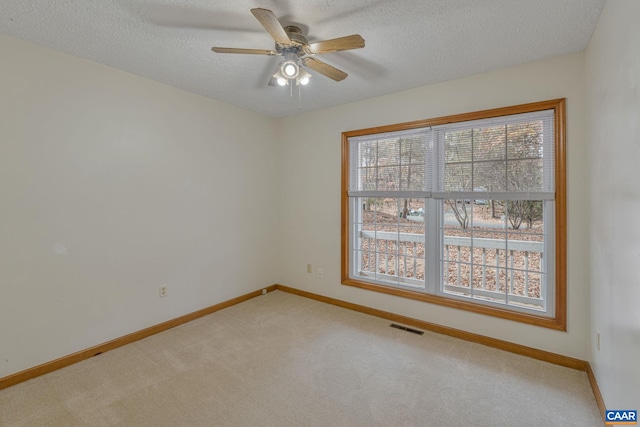 carpeted empty room with ceiling fan, a healthy amount of sunlight, and a textured ceiling