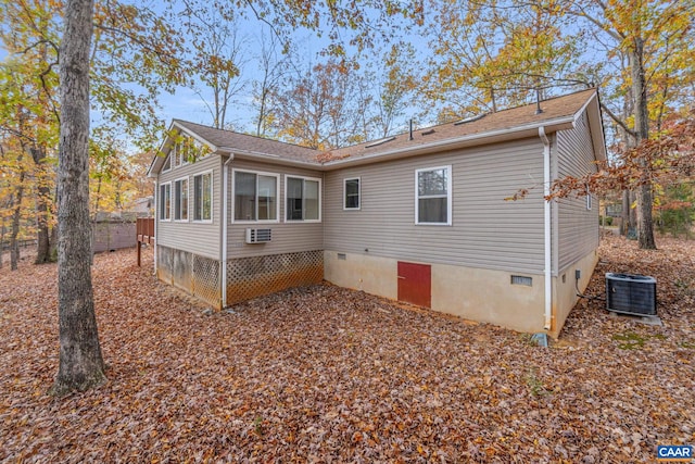 exterior space with a wall unit AC, central AC, and a sunroom